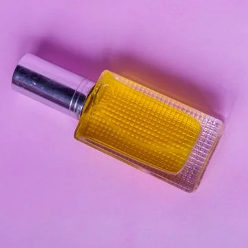 Perfume with yellow liquid on a pink solid background, watches, women's fashi Stock Photos
