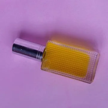 Perfume with yellow liquid on a pink solid background, watches, women's fashi Foto stock