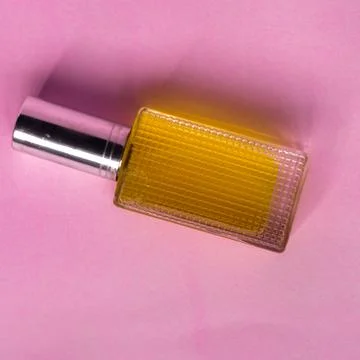 Perfume with yellow liquid on a pink solid background, watches, women's fashi Foto stock