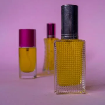 Perfume with yellow liquid on a pink solid background, watches, women's fashi Foto stock