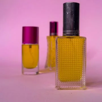 Perfume with yellow liquid on a pink solid background, watches, women's fashi Stock Photos