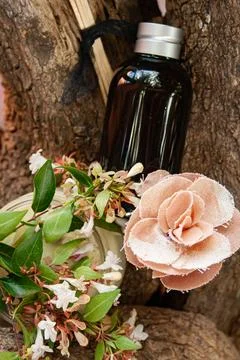 Perfumed essential oil on tree trunk decorated with flowers Stock Photos
