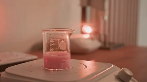 Perfumer Adding Powder to Pink Liquid in Beaker on Magnetic Stirrer Stock-Footage 337113727