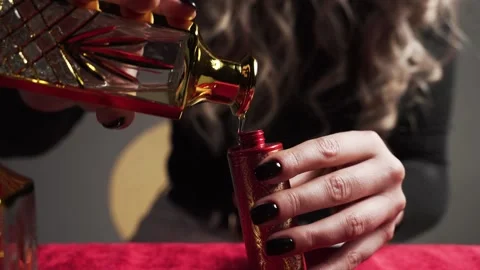 Perfumer pours perfume from glass bottle into small red vial Stock Footage 167740899
