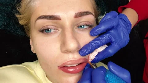 Permanent lip makeup. A close-up of a young woman doing lip makeup. Makeup 動画素材 161810570