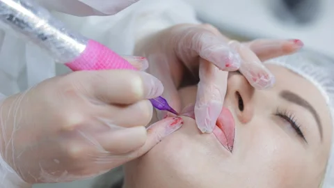 Permanent lip makeup procedure in progress, close-up of a beautician using Stock Footage 311074648