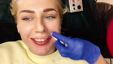 Permanent lip makeup. Top view of a young blue-eyed woman with a tattoo of her 스톡 동영상 162418129