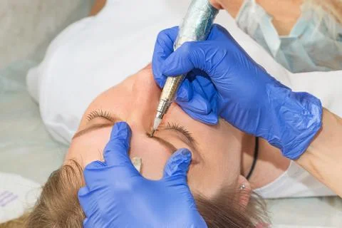 Permanent make up eyeliner procedure, applying on young girl, close up Stock Photos