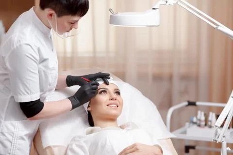 Permanent make-up wizard makes eyebrow correction procedure Stock Photos