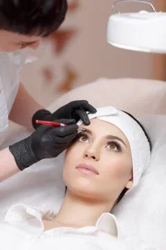 Permanent make-up wizard makes eyebrow correction procedure Stock Photos