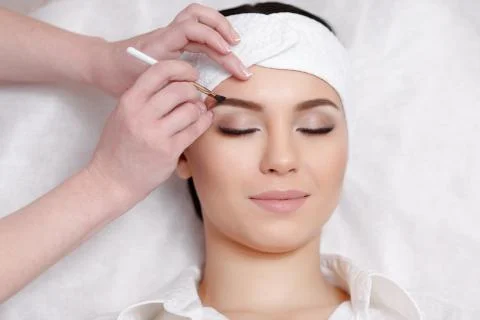 Permanent make-up wizard makes eyebrow correction procedure Stock Photos