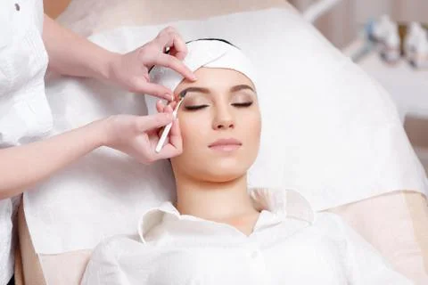 Permanent make-up wizard makes eyebrow correction procedure Stock Photos