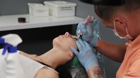 A permanent makeup artist gets a tattoo on a woman's upper eyelids. 库存影片 137540366