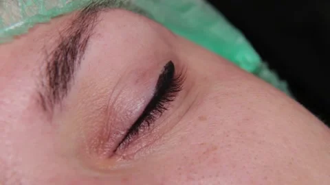 A permanent makeup artist gets a tattoo on a woman's upper eyelids. Video stock 137547568