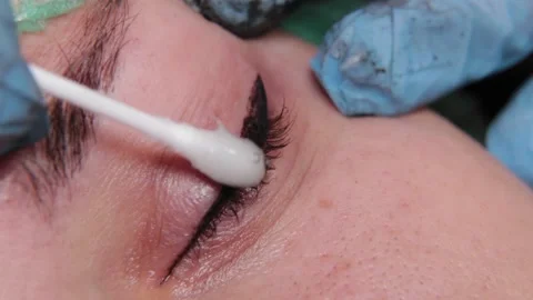 A permanent makeup artist gets a tattoo on a woman's upper eyelids. 库存影片 137547587
