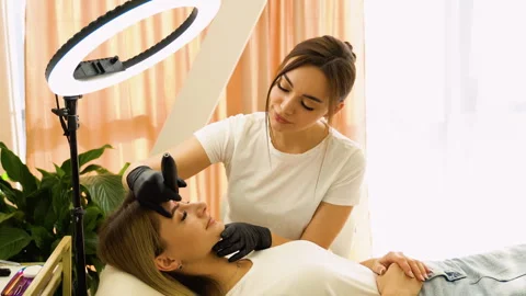 Permanent makeup artist makes eyebrow makeup in a beauty salon Stock Footage 255284022
