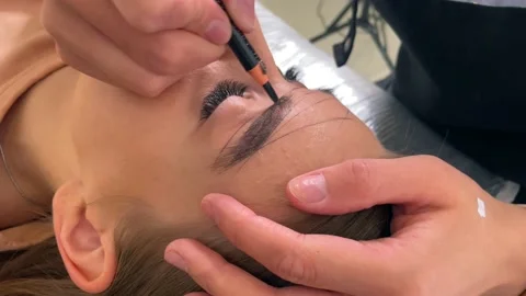 Permanent makeup eyebrow close-up view. Master draws a contour of eyebrows Stock Footage 200481390