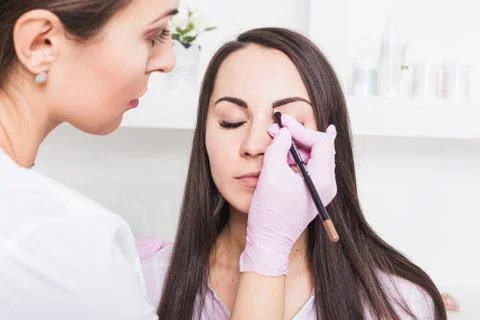 Permanent makeup for eyebrows of beautiful young woman in beauty salon Stock Photos