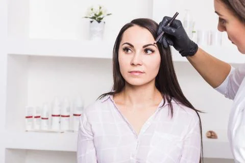 Permanent makeup for eyebrows of beautiful young woman in beauty salon Stock Photos