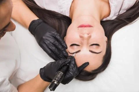 Permanent makeup for eyebrows of beautiful young woman in beauty salon Stock Photos