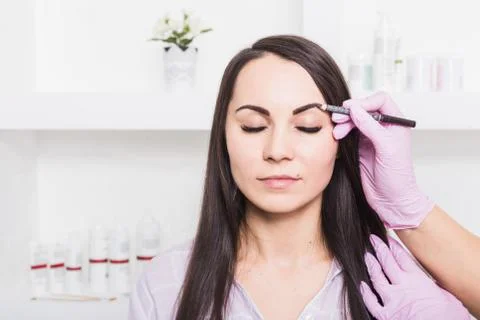 Permanent makeup for eyebrows of beautiful young woman in beauty salon Stock Photos