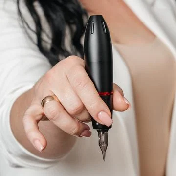 Permanent makeup machine in the hands of a master Fotos Stock