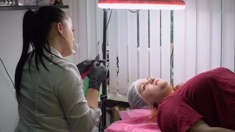 Permanent makeup master sets up the tattoo machine before permanent eyebrow Stock Footage 244261735