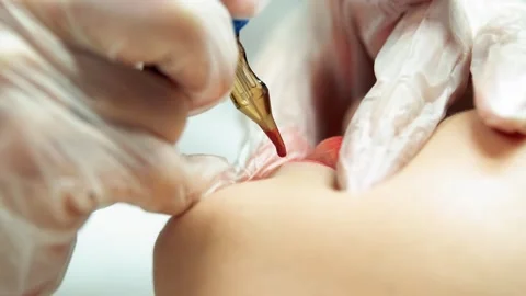 Permanent makeup paint is applied to the client's lips using a tattoo needle Stock Footage 264059274