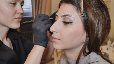Permanent makeup. Permanent tattooing of eyebrows. Cosmetologist applying Stock Photos