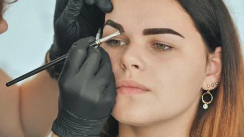 Permanent makeup. Permanent tattooing of eyebrows. Cosmetologist applying Stock Photos