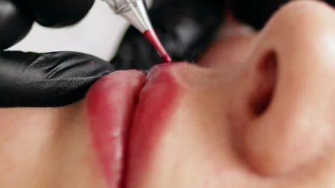 Permanent makeup procedure applying pink color pigment using tattoo machine Stock Footage 255410116