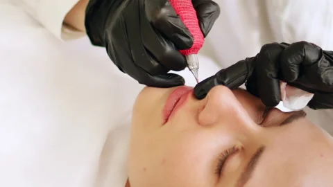 Permanent makeup procedure applying pink color pigment using tattoo machine Stock Footage 255420680