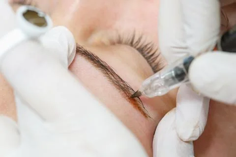 Permanent makeup, tattooing of eyebrows. Cosmetologist applying make up Stock Photos