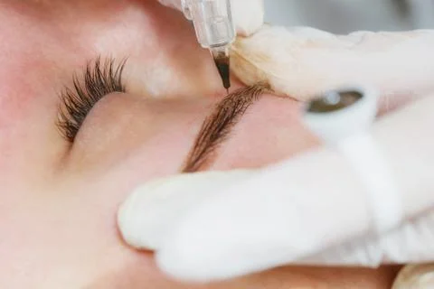 Permanent makeup, tattooing of eyebrows. Cosmetologist applying make up Stock Photos