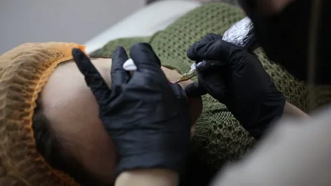 Permanent tattoo master put color pigment to client lips Stock Footage 151899330