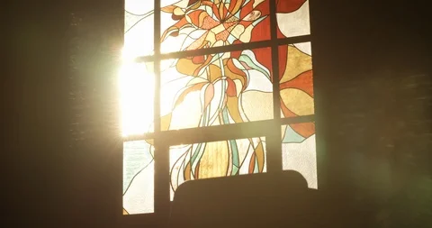 A peron walks through sunlight in front of church stained glass window Stock Footage 114070573