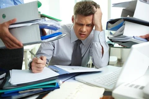 Perplexed accountant doing financial reports being surrounded by business partne Stock Photos