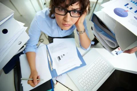 Perplexed accountant looking at camera while doing financial reports Stock Photos