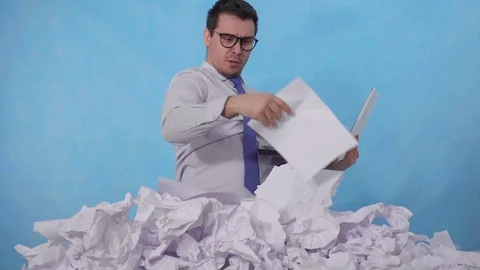 Perplexed man office worker with a laptop in a large heaps of crumpled paper Stock Footage 123009699