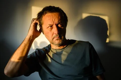 Perplexed man scratching his head with a confused expression, dramatic wind.. Stockfoto's