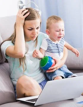 Perplexed woman is having issue with work while child crying Stock Photos