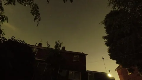 Persied meteor shower time lapse over homes rooftop fast moving night sky clouds Stock Footage 343082269