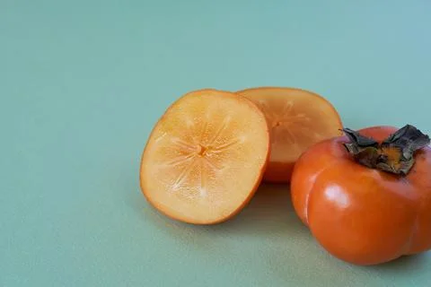 Persimmon fruit on a green background. Space for text. Stock Photos