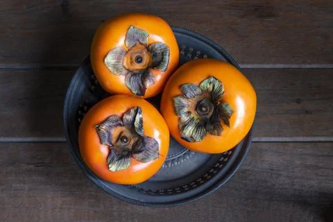 Persimmon fruit in tray on background top view. Stock Photos