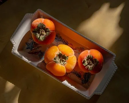 Persimmon on a plate in the setting sun Stock-Fotos