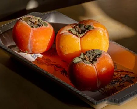 Persimmon on a plate in the setting sun Foto stock