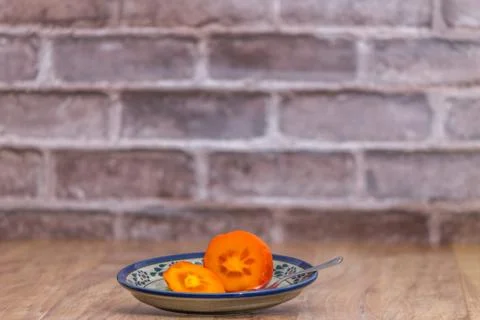 Persimmon ready to eat on rustic plate Foto stock