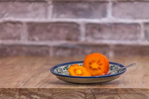 Persimmon ready to eat on rustic plate Stock Photos