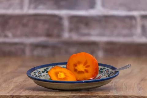 Persimmon ready to eat on rustic plate Stock Photos