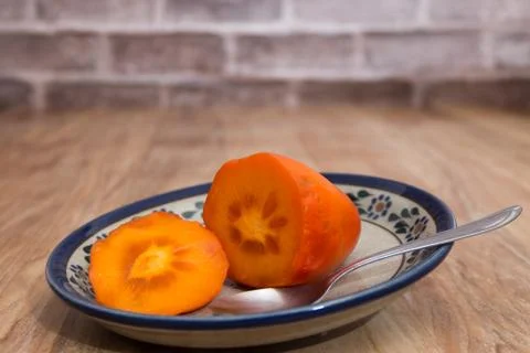 Persimmon ready to eat on rustic plate Stock Photos